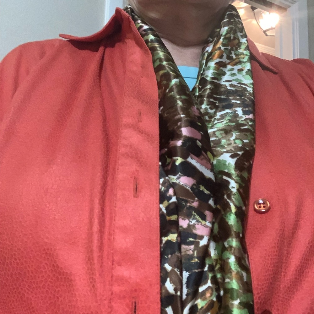Handmade scarf made from shiny material with green, brown, offwhite, and orange.